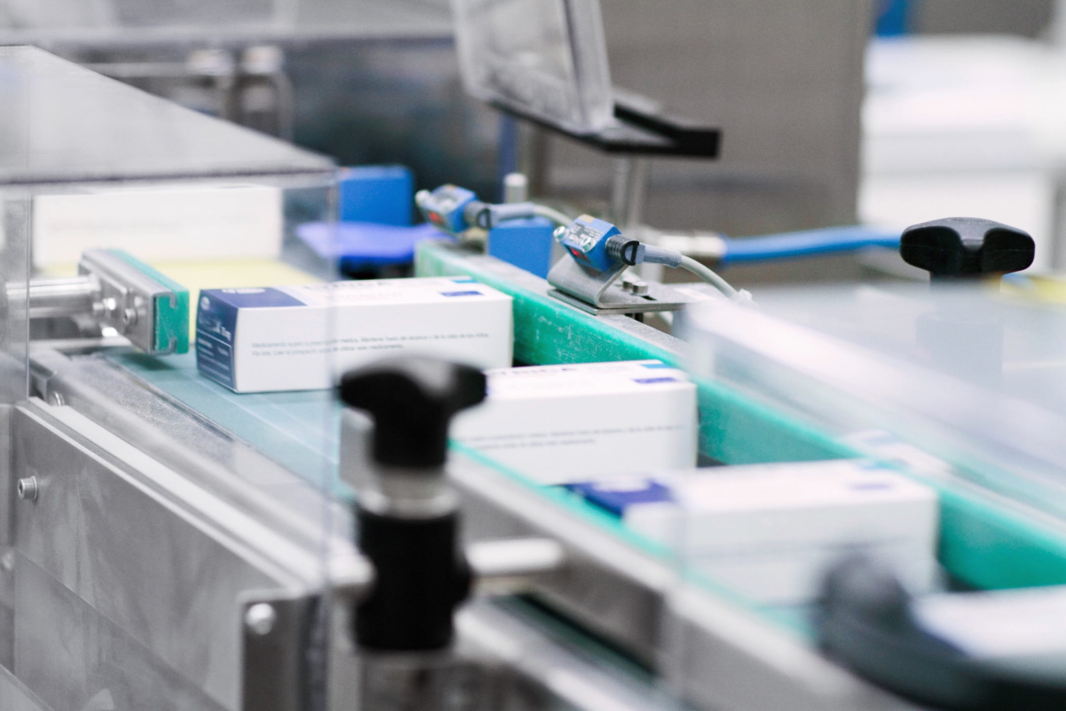 Boxes of medication moving down an automated factory assembly line.