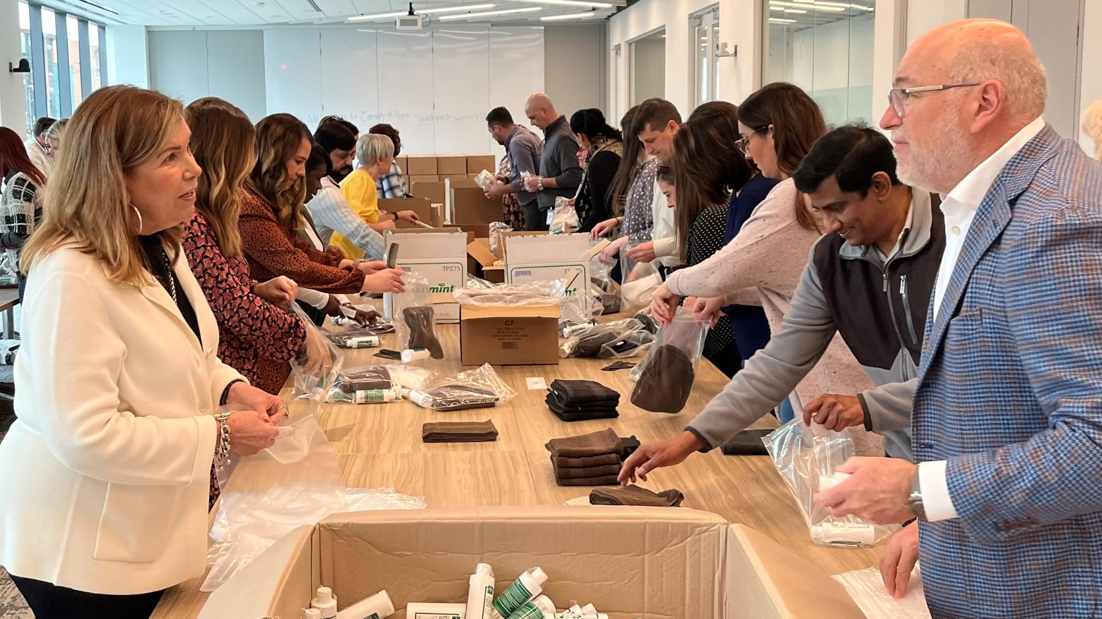 Two rows of volunteers in an office packing hygiene kits for military veterans that were distributed in local communities through our Red Cross partnership.