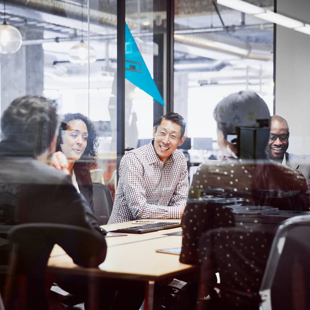 A diverse group of employees are gathered in a meeting room.