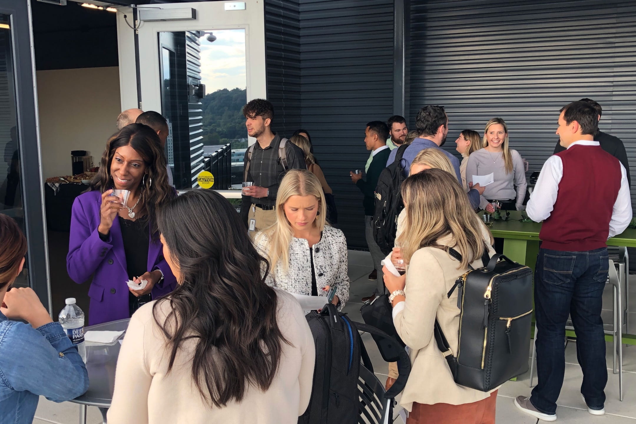 A diverse group of nineteen professionals meeting and chatting during a networking event. They are dressed casually and many of them hold refreshments.